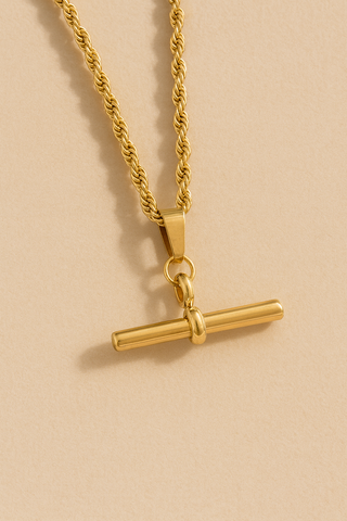 Gold necklace with a bar pendant on a beige background