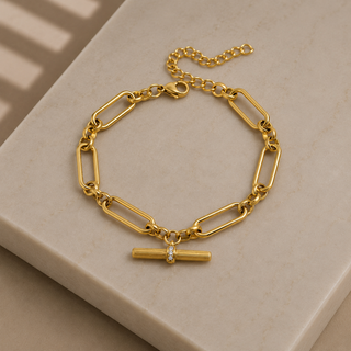 Gold chain bracelet with a clasp on a beige surface