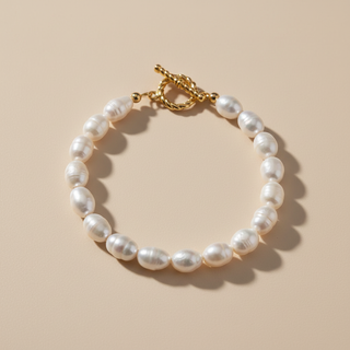 Pearl bracelet with gold clasp on a beige background
